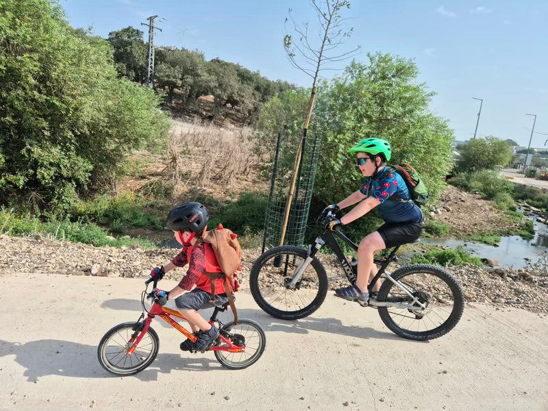 דוד ואריאל רוכבים על הטיילת לאורך נחל ציפורי